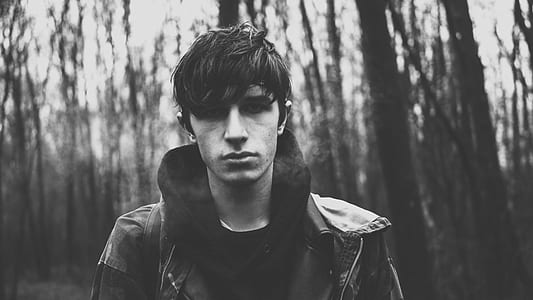 grayscale photo of man in forest thumbnail