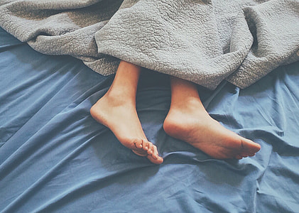 person laying on blue bed with gray blanket thumbnail