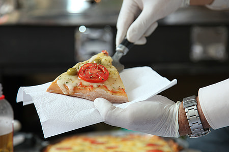 person wearing white gloves putting a slice of pizza on white tissue thumbnail