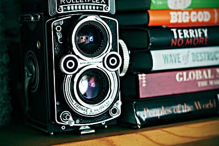 black twin lens camera beside books thumbnail