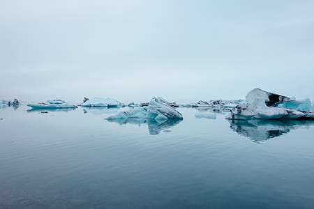 black stone covered by snow on body of water thumbnail