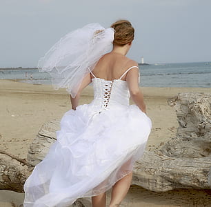 woman wearing wedding dress running on seashore near driftwood thumbnail