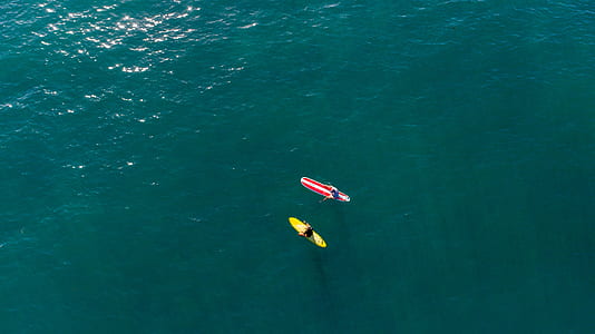 two red and yellow surfboards in body of waters thumbnail