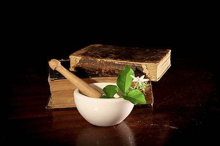 white ceramic bowl with white flower and brown wooden stick infront of two hardbound books thumbnail