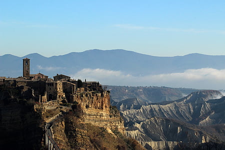 gray castle near rock cliffs under blue sky thumbnail