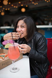 Woman Wearing Black Leather Jacket Eating Pizza thumbnail