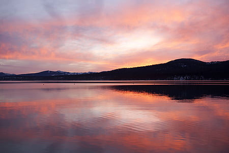 silhouette of mountain beside body of water during sunset thumbnail