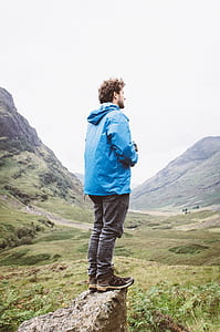 man standing on cliff near mountains thumbnail