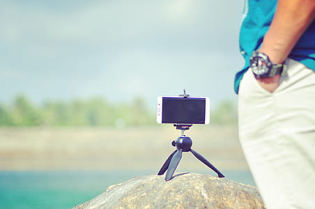 Turned Off White Android Smartphone With Mini Tri Stand on Rock thumbnail