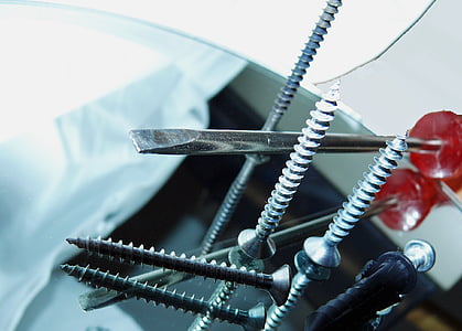 red handled slot-head screwdriver and screws on table thumbnail