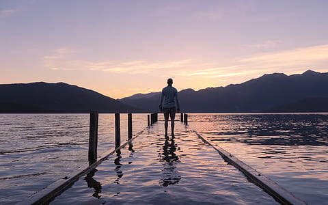 person walking on docked facing mountains thumbnail