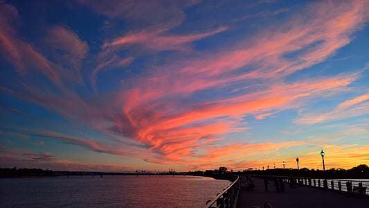 people on wooden dock by the water under blue and orange sky during sunset thumbnail