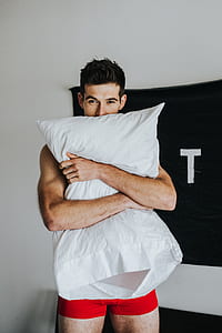 man hugging white bed pillow thumbnail