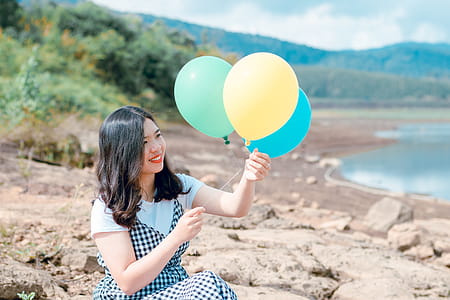 Woman in White and Black Dress Holding Three Balloons thumbnail