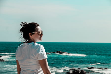Woman Wearing White T-shirt With Distance at Sea With Rock Formations thumbnail