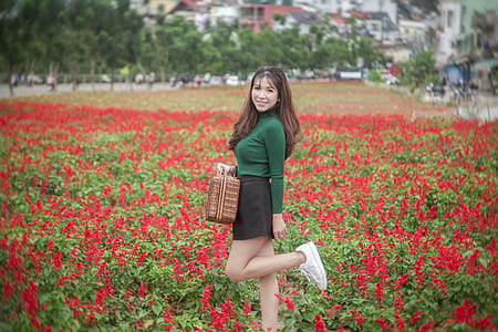 smiling woman standing on red flower field thumbnail