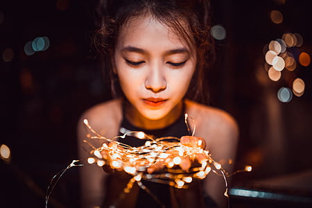 shallow focus photography of woman holding string lights thumbnail