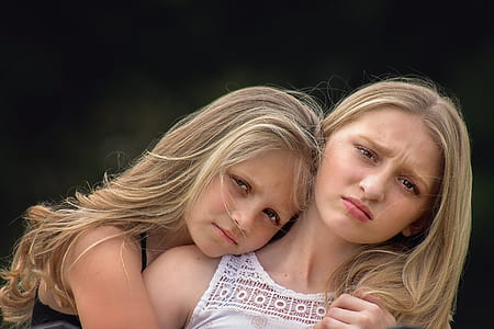 blonde haired girl in black spaghetti strap top hugging woman in white sleeveless top thumbnail