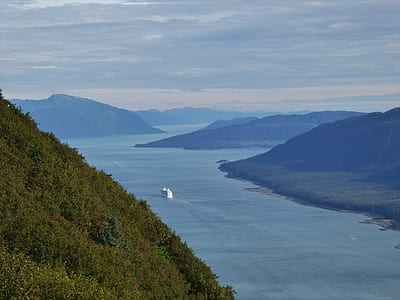 white boat on body of water near mountain thumbnail