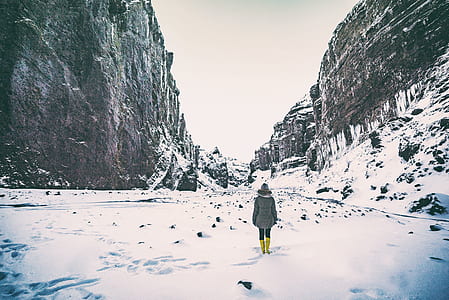person in coat walking in the middle of snowy mountain thumbnail