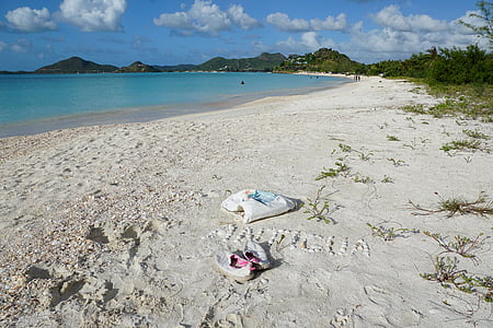 pair of white slip-on shoes on white sand beach thumbnail