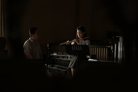 woman playing flute in front of man thumbnail