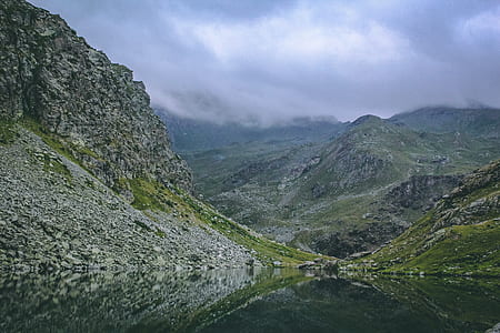 Gray and Green Mountains With Body of Water Under Cloudy Sky thumbnail