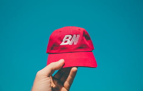 person holding red New Balance cap thumbnail