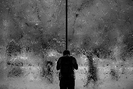 person carrying backpack standing near glass window thumbnail