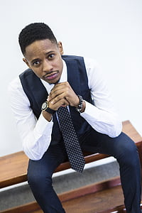 man wearing blue vest sitting on wooden bench thumbnail