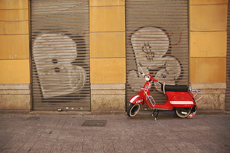 red and black motor scooter parked beside building thumbnail