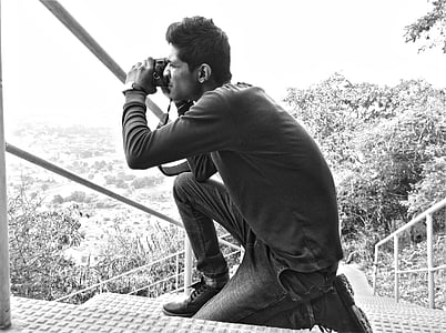grayscale photo of man using DSLR camera thumbnail