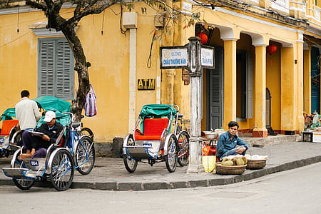 man sitting near gray and green cart near road thumbnail