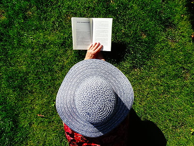 person wearing gray sun hat holding book thumbnail