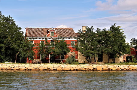 red paint house near river at daytime thumbnail