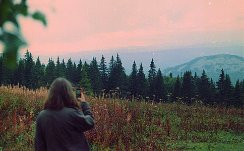 woman taking photo of trees and mountains thumbnail