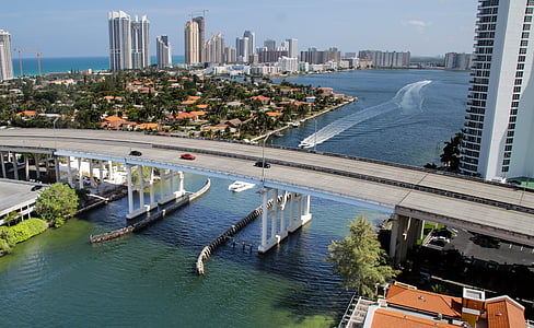 white yacht maneuvering under gray concrete bridge under daytime thumbnail