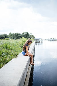 woman sitting beside body of water thumbnail