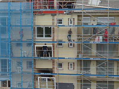 three men standing on building scaffolding during daytime thumbnail