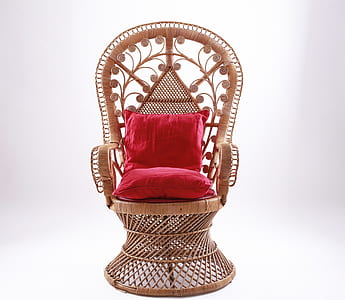 brown wicker armchair with red throw pillows thumbnail