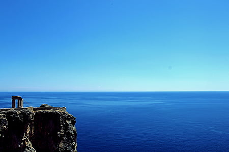 gray rugged cliff near blue calm body of water under blue sky at daytime thumbnail