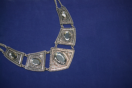 silver-colored clear gemstone encrusted bib necklace on blue textile thumbnail