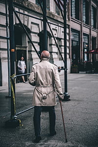 man using cane while walking on street in front of building thumbnail