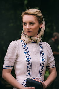 woman wearing white and blue floral dress holding black leather wallet thumbnail