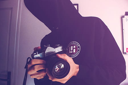 Man Holding Black and Gray Dslr Camera Inside White Wall Paint Room thumbnail