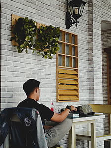 man sitting on chair in front of table beside window thumbnail