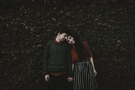 man and woman taking photo in front of plant wall thumbnail