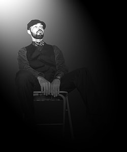 grayscale photo of man sitting on chair thumbnail