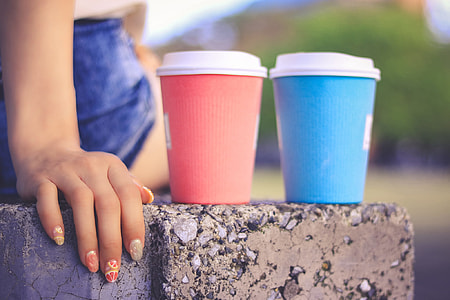 two pink and blue disposable drinking cups beside each other on gray concrete bench thumbnail