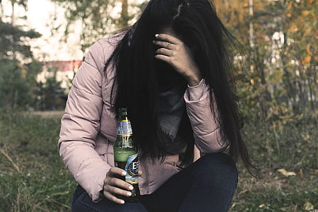 woman holding beer while holding her head thumbnail